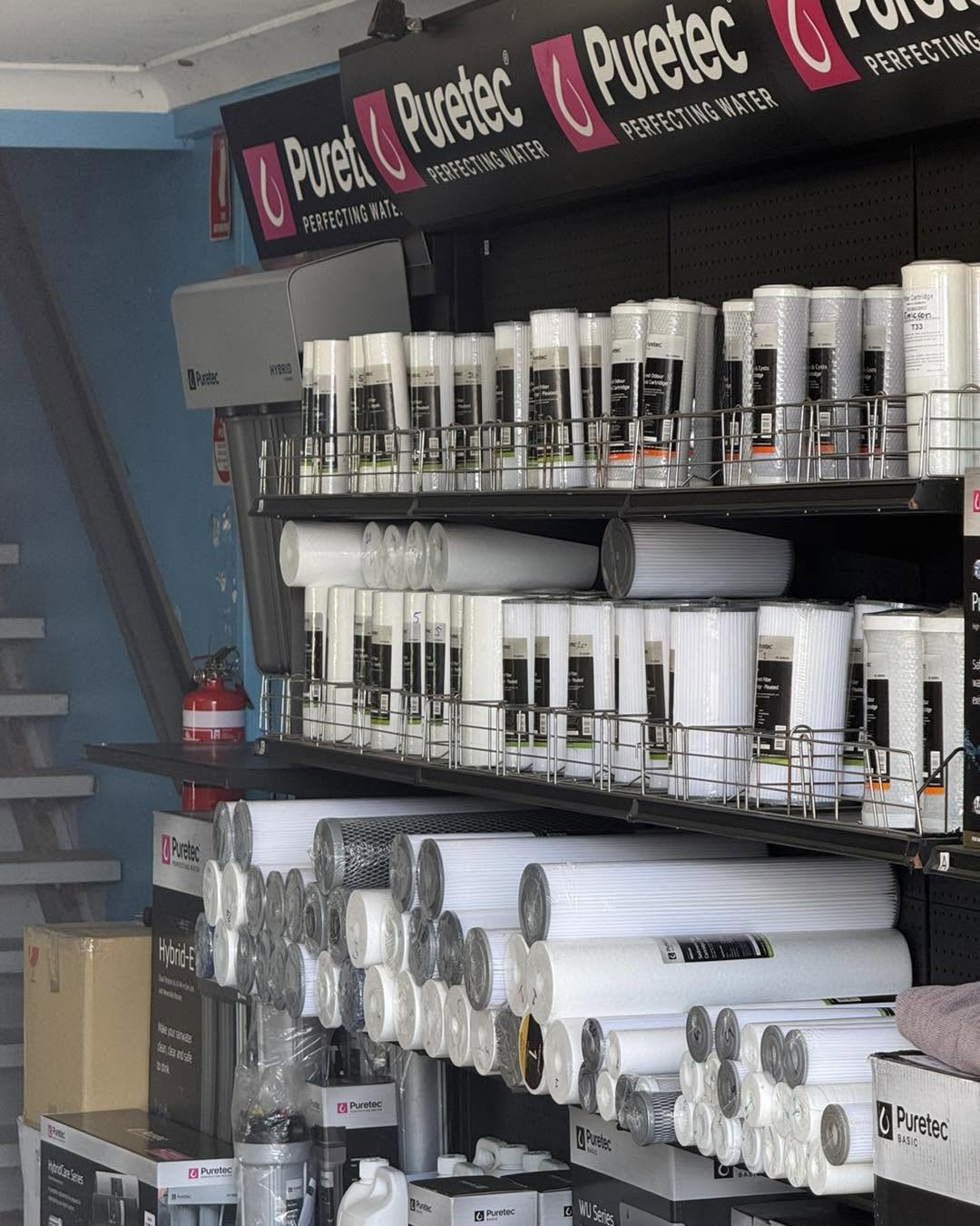 The Puretec filtration wall inside the shop, racked with sediment and carbon cartridges of every size.